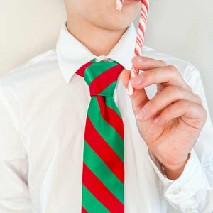 Boy wearing a red and green striped tie while eating a candy cane