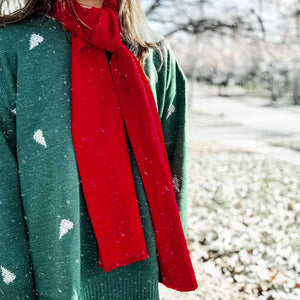 Woman wearing a red winter scarf with a holiday themed sweatshirt