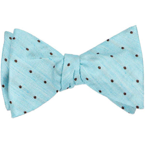 A tied self-tie bow tie in a light blue with small brown polka dots