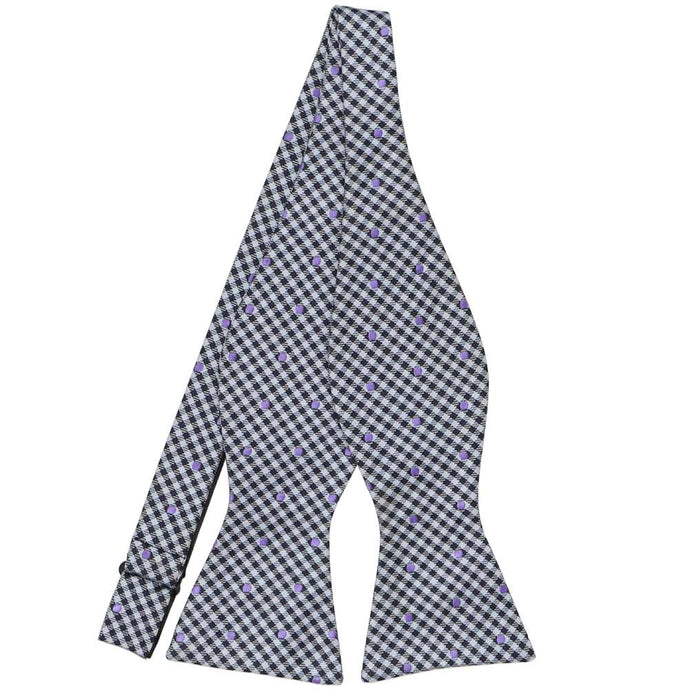 A gingham self-tie bow tie in shades of blue with purple polka dots, untied